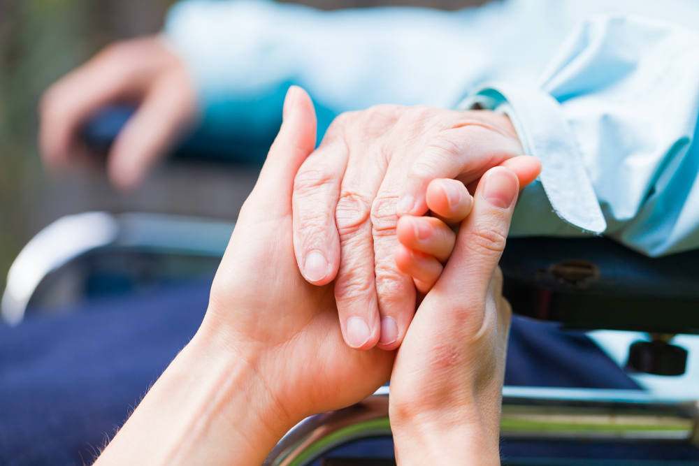 Volunteer holding hands with woman in wheelchair